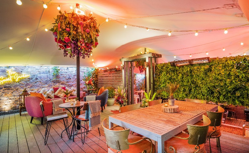 Tables and chairs on the covered terrace in The Square's Secret Garden